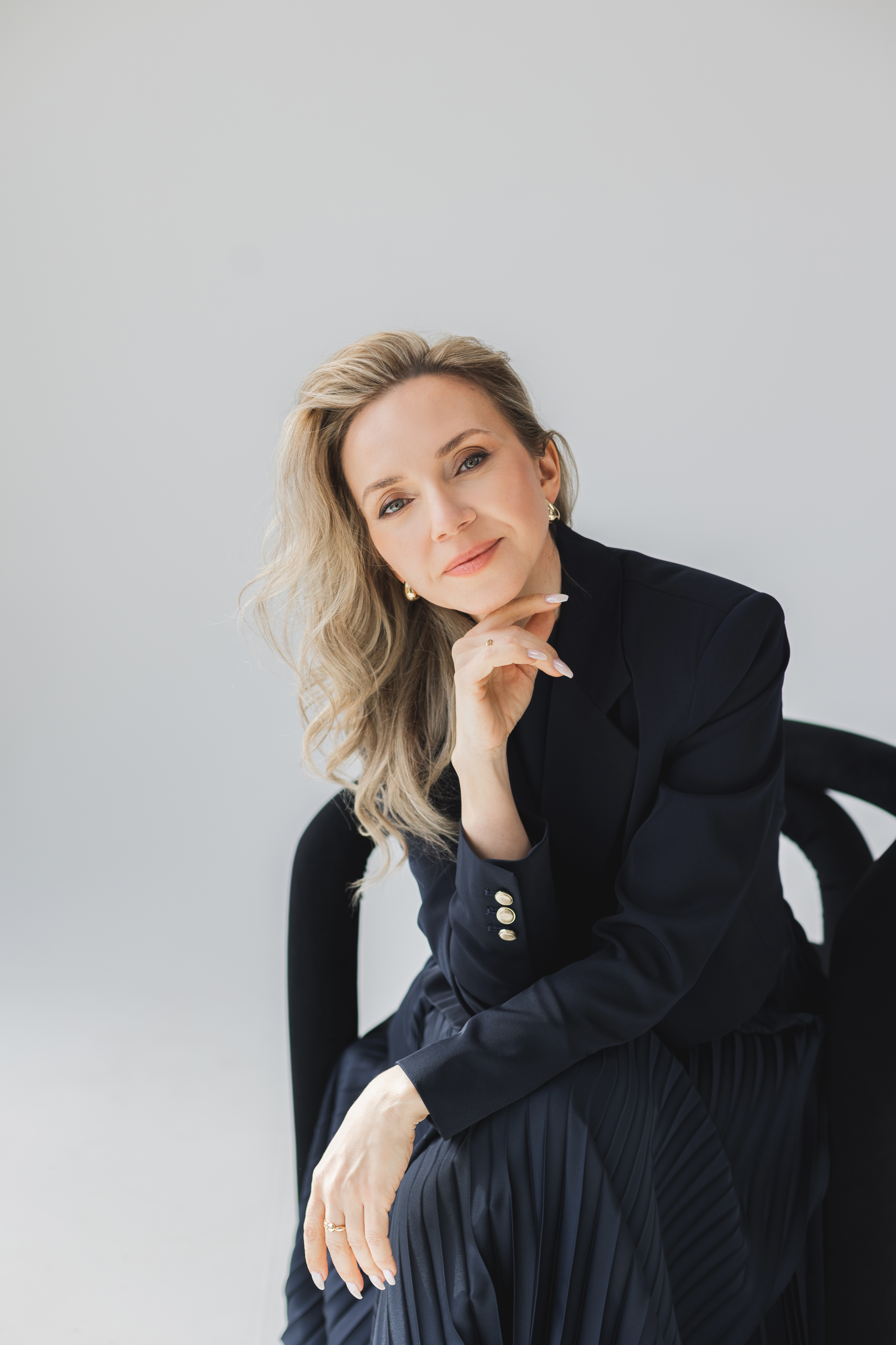 Yana Mamotenko in a navy blazer, resting her chin on her hand with direct eye contact